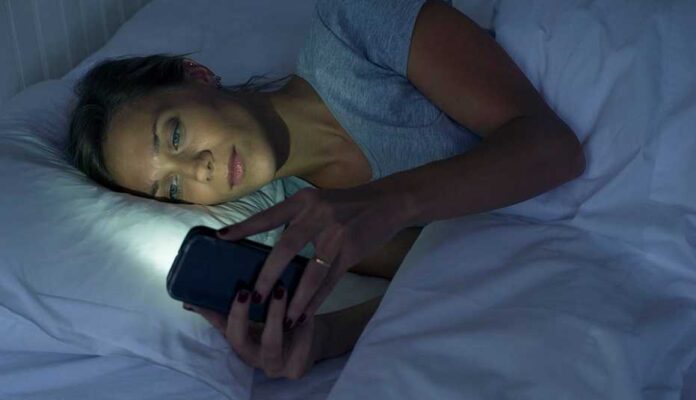 1140-woman-lying-in-bed-using-smartphone-esp